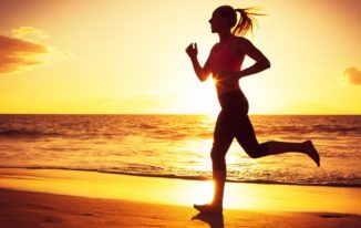 Woman running on the beach at sunset evening workout